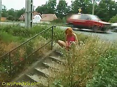 Girl takes a piss next to a public street